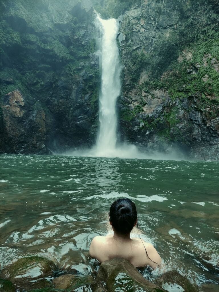 Pessoa nadando perto de cachoeira imponente
