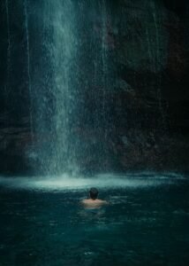 Pessoa nadando sob cachoeira em poço natural