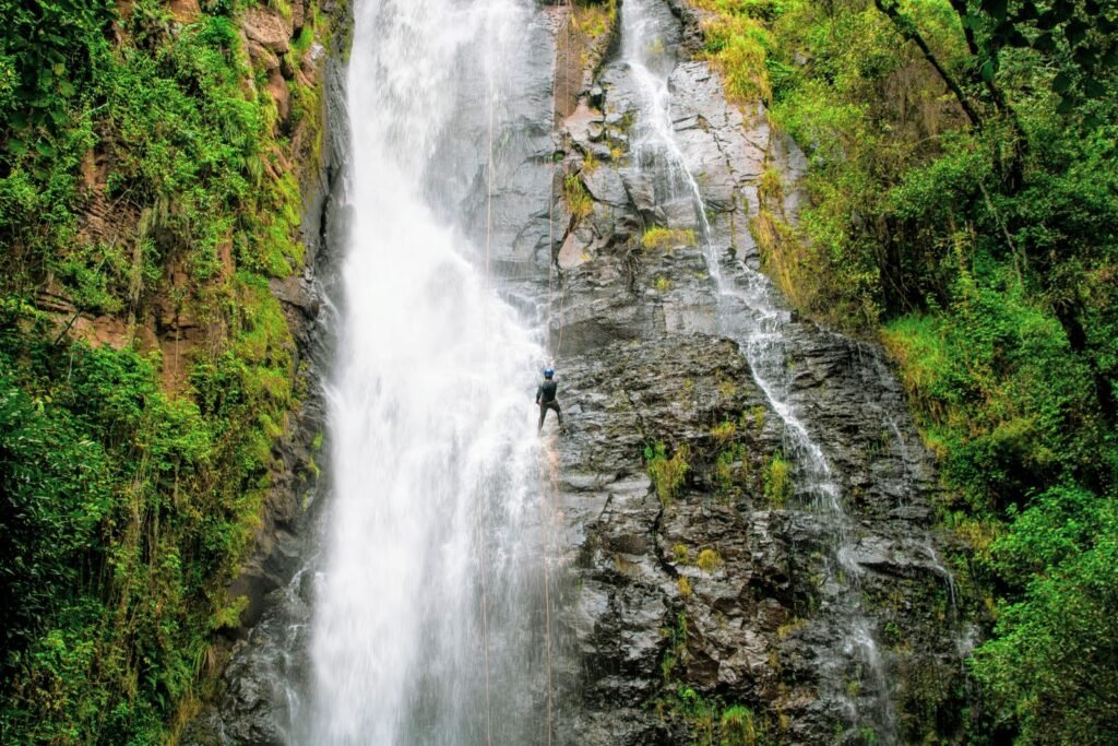Aventureiro com cordas em cachoeira cercada de vegetação