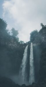 Cachoeira alta em meio à mata e névoa