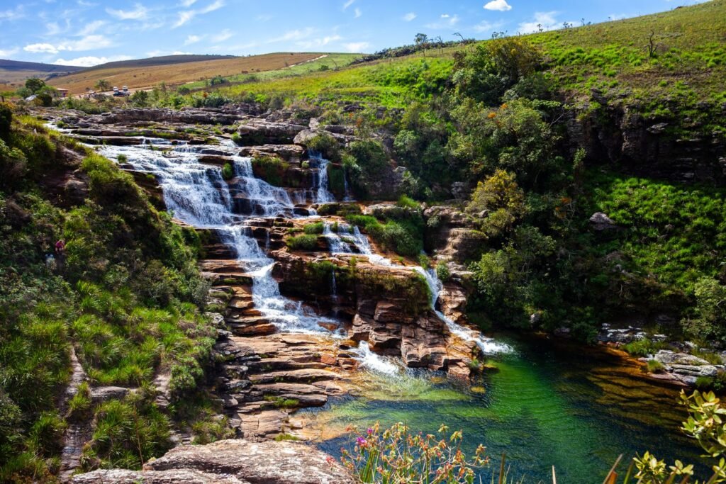 Cachoeira em degraus com poço claro cercada de vegetação verde