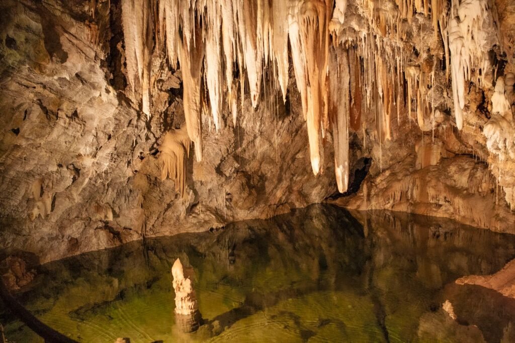 Interior de caverna com lago subterrâneo espelhado refletindo estalactites