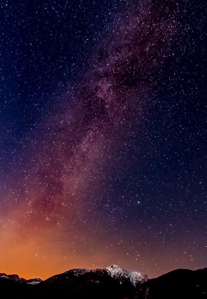 Via Láctea brilhando no céu noturno sobre silhueta de serras