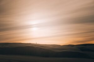 Pessoa solitária caminhando em dunas ao pôr do sol