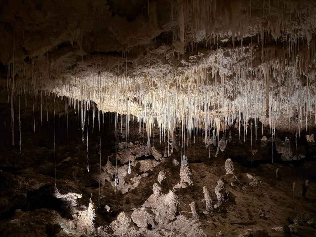 Estalactites pendendo do teto de caverna com jogo de sombras