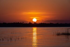 Lagoa de águas calmas refletindo o céu dourado do nascer do sol em Jericoacoara, Ceará