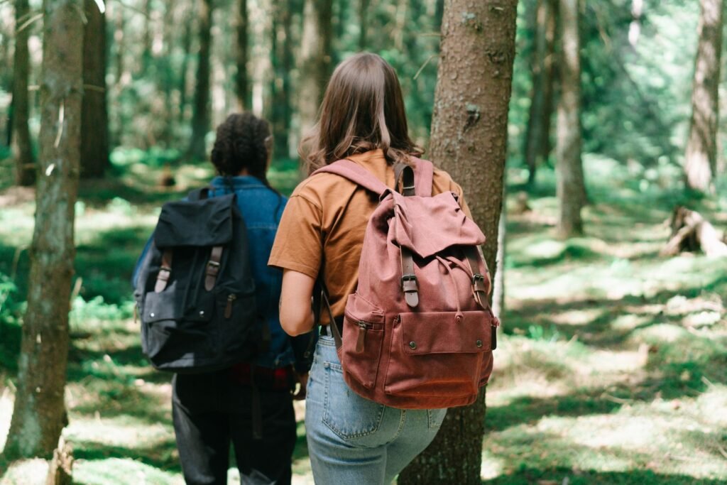 Dois ecoturistas caminhando com mochilas em trilha cercada de vegetação