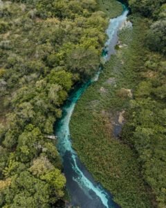 Vista aérea de rio de águas azul-turquesa cercado de mata em Mato Grosso