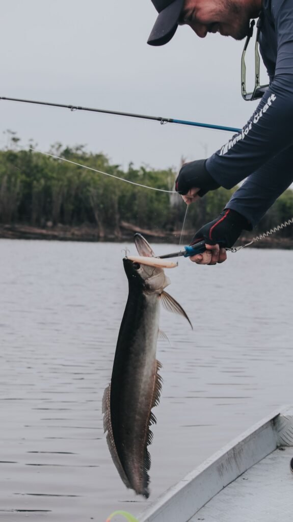 Pescador com vara em barco em rio de água escura