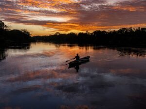 Pescador em canoa no rio amazônico ao entardecer