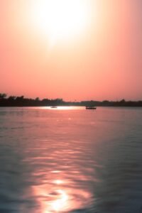 Barco navegando em rio tropical calmo ao pôr do sol