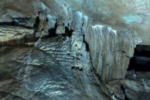 Interior de caverna com grandes estalactites e estalagmites iluminadas
