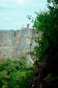 Aventureiro em tirolesa sobre cânion com vegetação