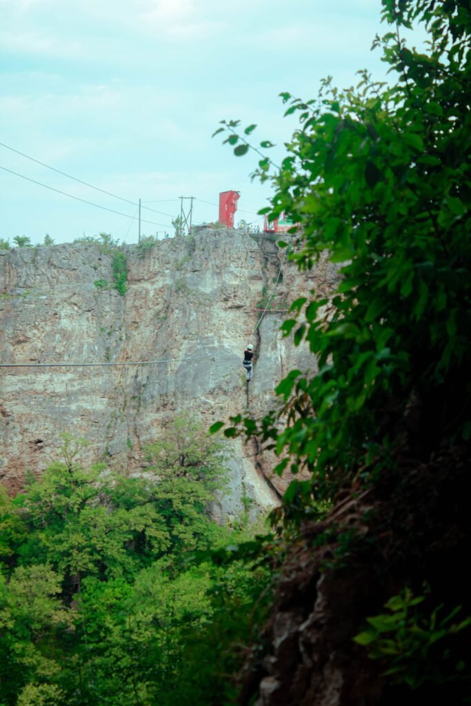 Aventureiro em tirolesa sobre cânion com vegetação