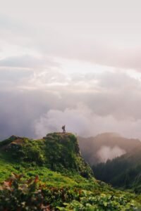 Pessoa no topo de montanha com nuvens ao amanhecer