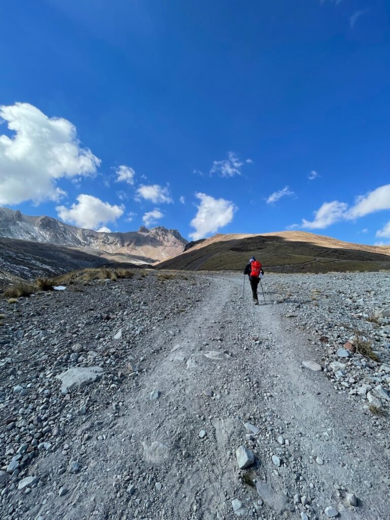 Trilheiro caminhando em terreno rochoso de montanha