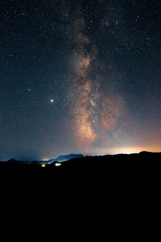 Via Láctea iluminando o céu noturno sobre serra silhuetada