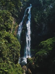 Cachoeira altíssima despencando de paredão cercado de mata tropical